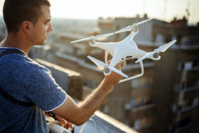 Young technician flying UAV drone with remote control outdoor